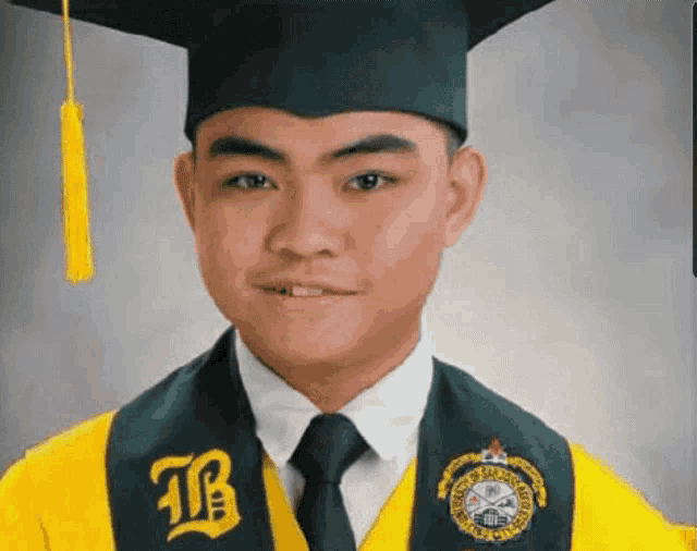 a man wearing a graduation cap and gown with the letter b on the sash