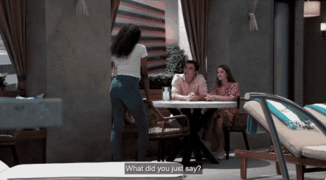 a man and a woman sit at a table while a woman stands behind them and says what did you just say