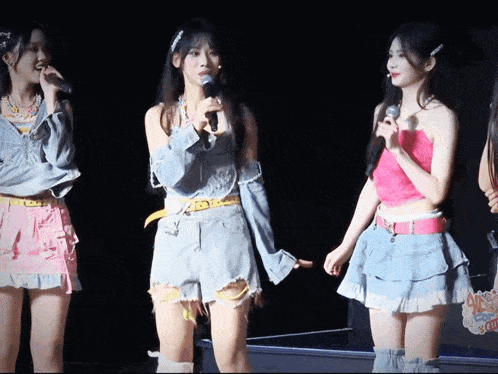 a girl in a pink top is holding a microphone while standing next to two other girls