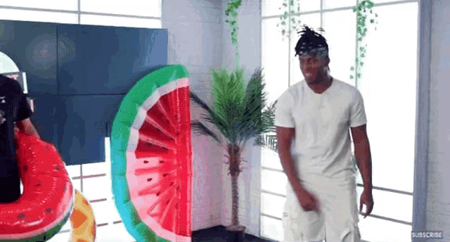 a man in a white shirt is standing in front of a watermelon float .