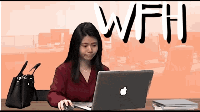 a woman sits at a desk using an apple laptop with the word wfh behind her