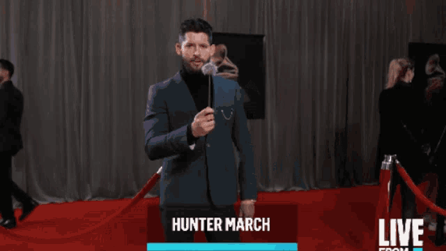 a man in a suit holds a dandelion in front of a grammophone and says hunter march on the bottom
