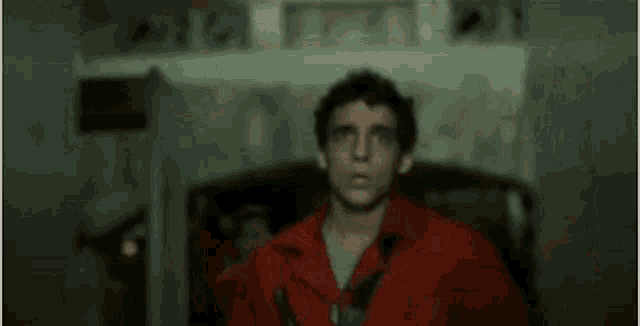 a group of men in red jackets are standing next to each other and one of them is covering his eyes with his hands .