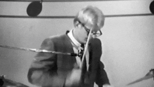 a man in a suit and tie is playing a drum set