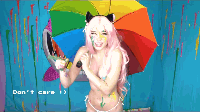 a woman in a bikini holding a rainbow colored umbrella with the words " don 't care " written below her