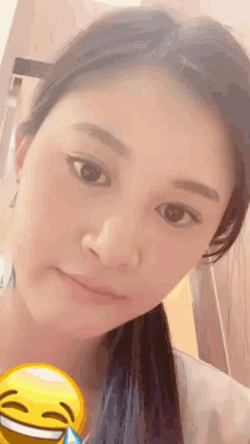 a close up of a woman 's face with a yellow smiley face in front of her