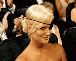 a woman wearing a black band around her head is smiling in a crowd of people