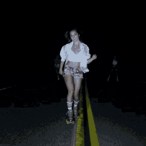 a woman is rollerblading down the road at night