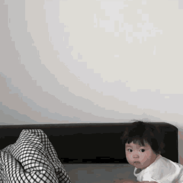a baby is laying on a bed with a white shirt on