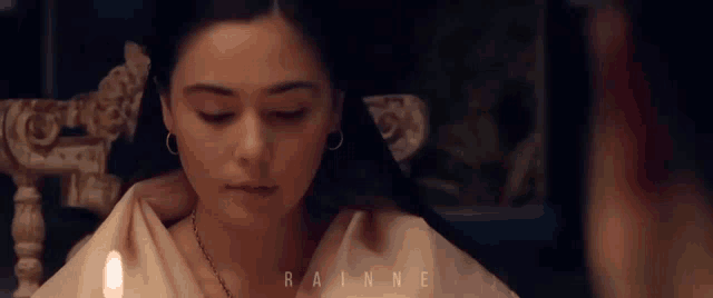 a woman sitting in a chair with a candle in front of her and the word rainne on the bottom right