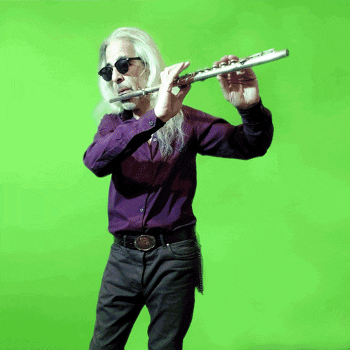 a man with long hair and sunglasses plays a flute