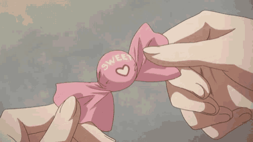 a person is holding a piece of pink paper with a red heart on it in their hands .