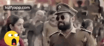 a man in a police uniform and sunglasses is standing in front of a crowd .