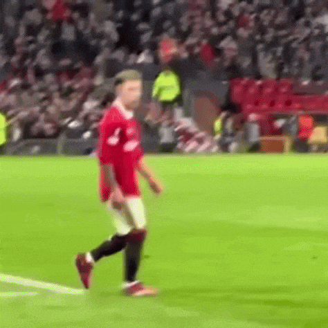 a soccer player in a red jersey is walking on the field .