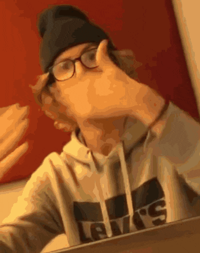 a man wearing glasses and a levi 's sweatshirt takes a selfie in front of a mirror