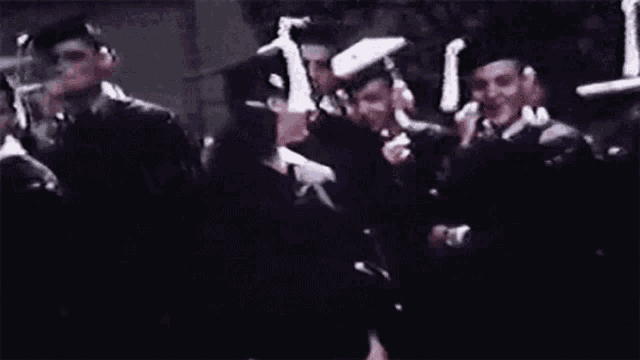 a woman in a graduation cap and gown is smiling while standing in front of a crowd of people .