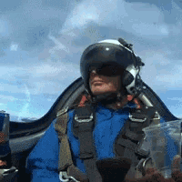 a man wearing a helmet and headphones sitting in a plane