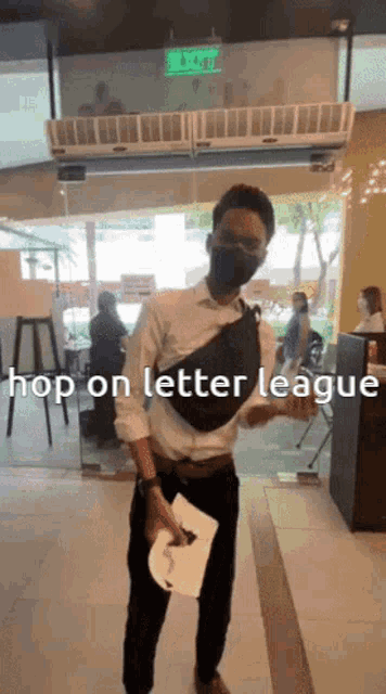 a man wearing a mask is holding a piece of paper that says hop on letter league on it