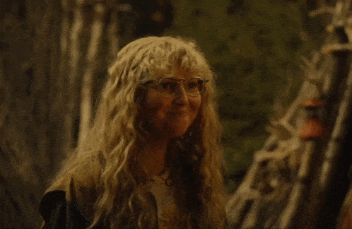 a woman with blonde hair and glasses covering her mouth with her hand