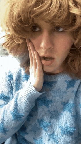 a woman with curly hair wearing a blue sweater