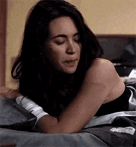 a woman with a bandaged arm is laying on a bed with her eyes closed .
