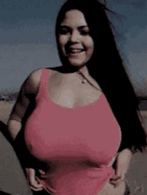 a woman with very large breasts is wearing a pink tank top .