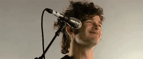 a man is singing into a microphone and smiling .