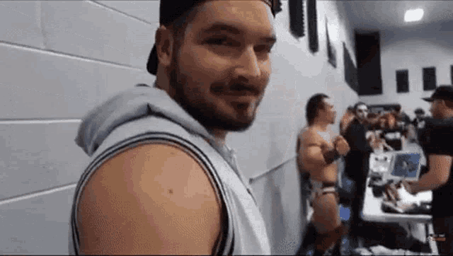 a man with a beard is standing in front of a group of people in a locker room .