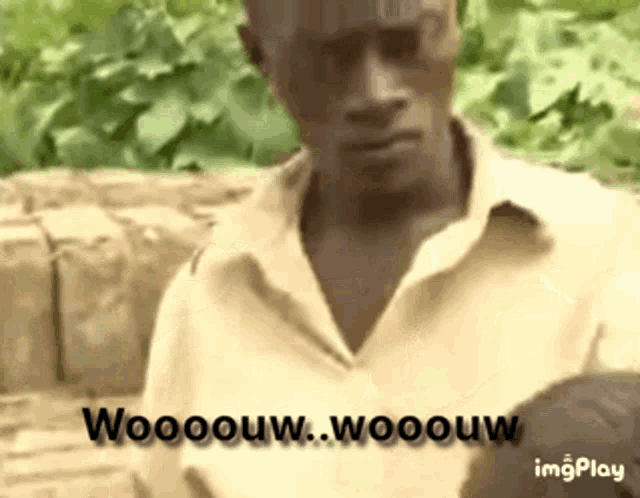 a man in a yellow shirt is standing in front of a brick wall and says woooow .
