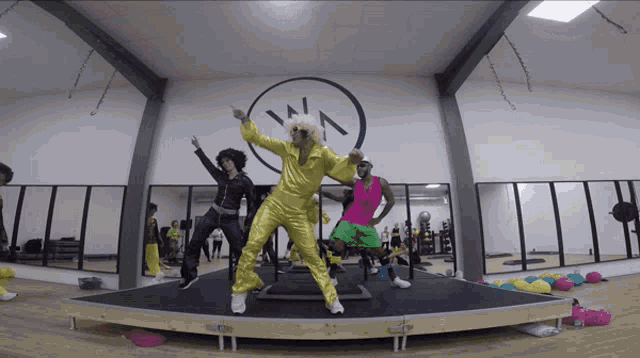 a group of people dancing in a gym with a smiley face on the wall behind them