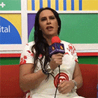 a woman is sitting on a red couch holding a microphone