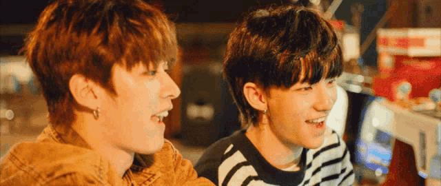 a couple of young men are sitting next to each other and smiling