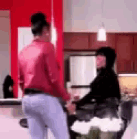 a woman in a red shirt is standing next to a man in a black shirt in a kitchen .