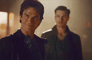 two men are standing next to each other in a dark room and smiling .