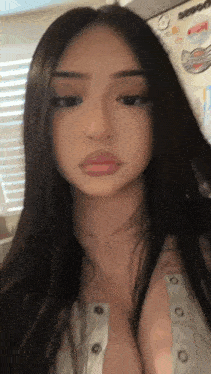a close up of a woman 's face with long dark hair and a white shirt .