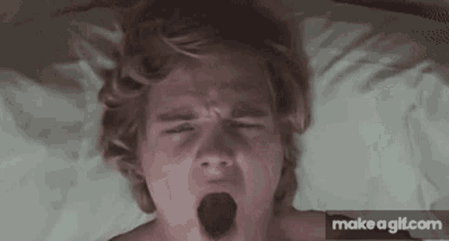 a man laying on a bed with his mouth open