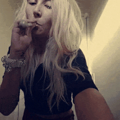 a blonde woman smoking a cigarette in a black shirt