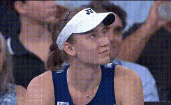 a woman wearing a white visor is sitting in a crowd .