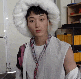 a young man wearing a white fur hat and a scarf around his neck .