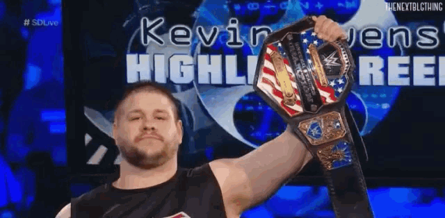 a wrestler is holding a wrestling championship belt in front of a blue background .