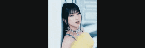 a close up of a woman wearing a yellow dress and a necklace .