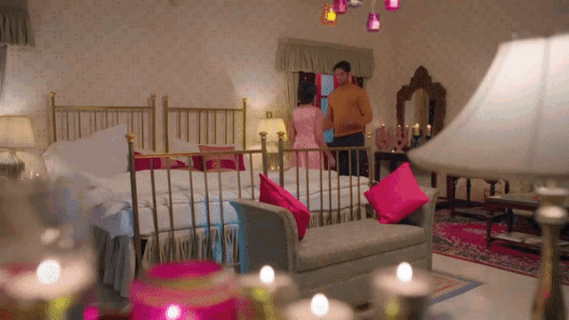 a man and woman standing in a bedroom with candles