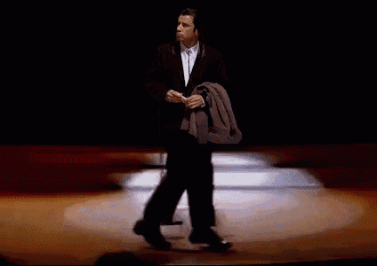 a man in a suit and tie is walking on a stage while holding a cup of coffee .