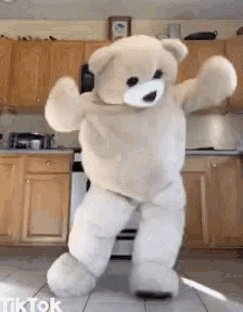 a giant teddy bear is dancing in a kitchen .