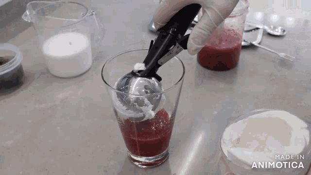 a blender is being used to mix a red liquid in a glass which says made in animotica on the bottom