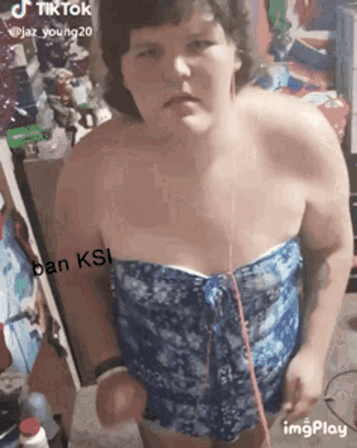 a woman in a blue strapless top is standing in a room with a caption that says ban ksi .