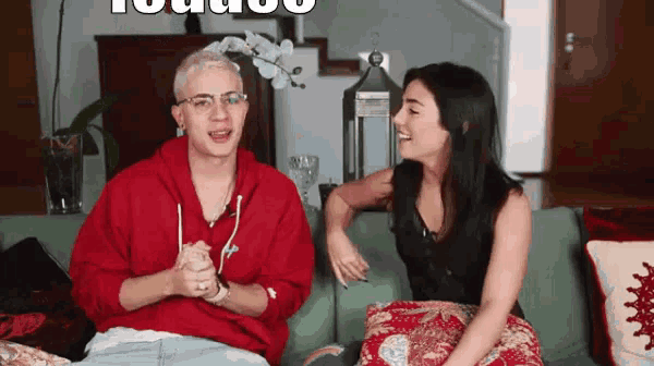 a man and a woman are sitting on a couch and talking to each other .