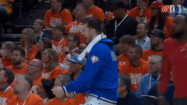 a man in a crowd wearing an orange take note shirt