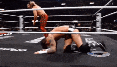 two men are wrestling in a ring and one of them is kneeling on the floor