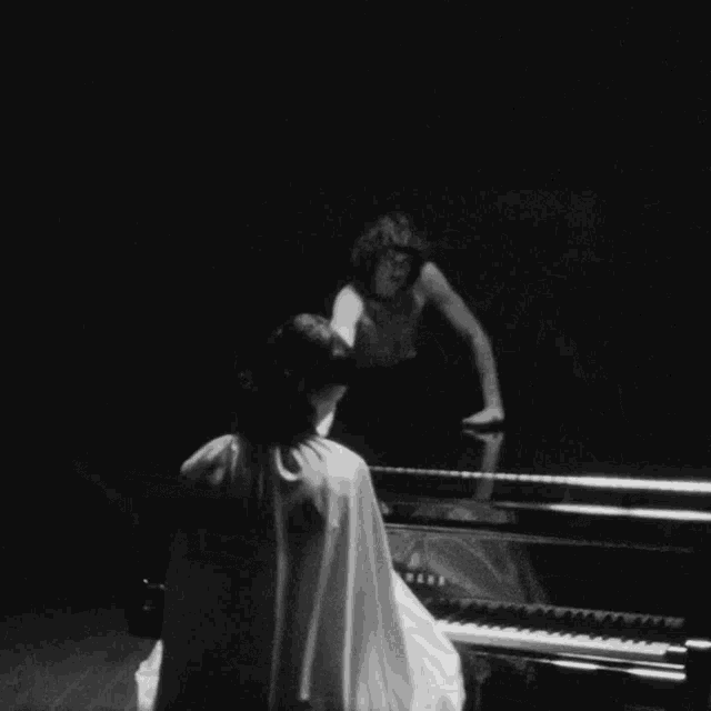 a black and white photo of a man playing a yamaha piano